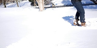 冬天，裹得严严实实的人用铁锹铲被雪覆盖的车道