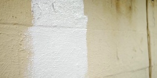 用滚轴在未完工的地下室墙面上涂上防水密封胶