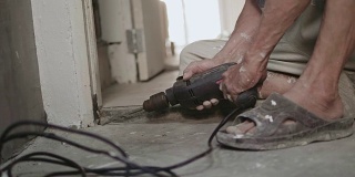 一个老人在家里用电钻做DIY。