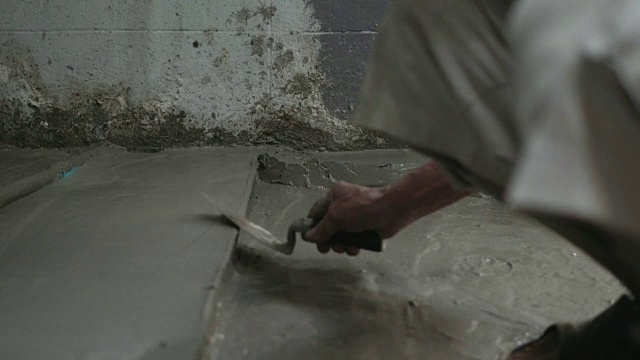 男人的手正在用泥铲抹地板。建筑工人在家。