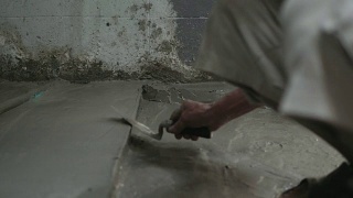 男人的手正在用泥铲抹地板。建筑工人在家。视频素材模板下载