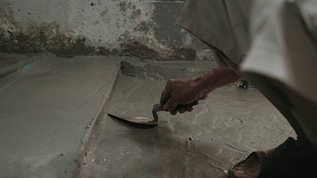 男人的手正在用泥铲抹地板。建筑工人在家。