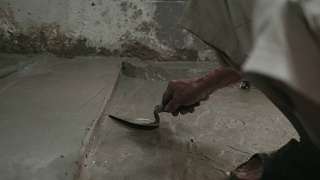 男人的手正在用泥铲抹地板。建筑工人在家。视频素材模板下载