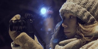 女孩摄影师拍摄户外雪冬夜灯光公园
