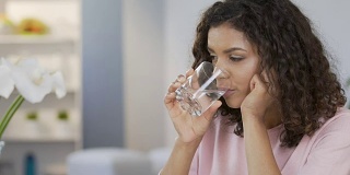 漂亮的混血女性喝着平静的水，享受着健康的生活方式
