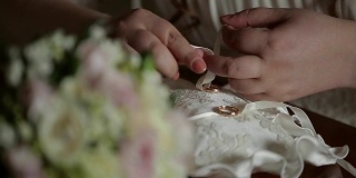 新娘的手的特写，结婚戒指绑定到一个美丽的pad