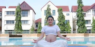孕妇在泳池边放松，做瑜伽