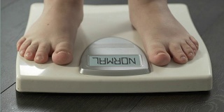 体重正常，女人踩着磅秤检查饮食结果，正面观