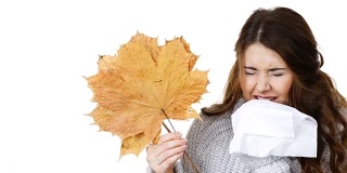 生病的女人用纸巾捂着秋叶打喷嚏