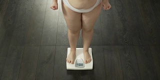 节食成功，胖嘟嘟的女士测量体重，对结果满意