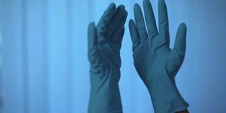 人们看着戴着乳胶手套的手，在刺激下脱下它们
