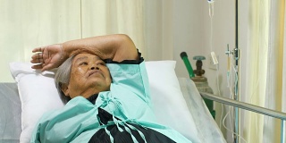 资深妇女因疼痛和失眠在医院病床上接受静脉滴注康复治疗
