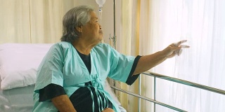 老年妇女坐在病床上和躺在医院里，悲伤的残疾人在病床上感到孤独。退休妇女独自在诊所里。