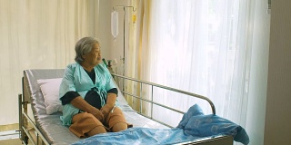 老年妇女坐在病床上和躺在医院里，悲伤的残疾人在病床上感到孤独。退休妇女独自在诊所里。