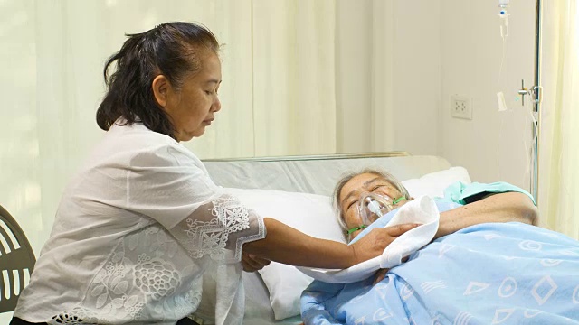 一位妇女正在医院病床上照顾她的母亲
