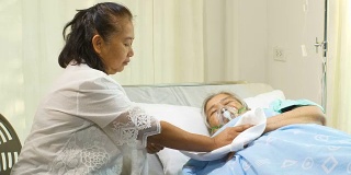 一位妇女正在医院病床上照顾她的母亲