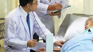 Doctor with stethoscope checking patient's blood pressure of old woman on the bed视频素材模板下载