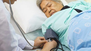 医生在床上用听诊器检查老妇人的血压视频素材模板下载