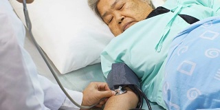 医生在床上用听诊器检查老妇人的血压