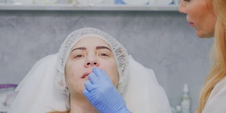 美容师给病人注射肉毒杆菌后温暖嘴唇