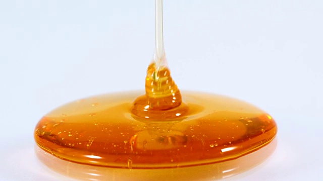近浇金色甜蜜的蜂蜜滴在白色的背景，4K Dci分辨率