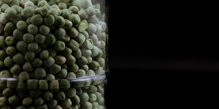 绿色的豌豆孤立地落在一个罐子的黑色背景中