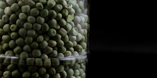 绿色的豌豆孤立地落在一个罐子的黑色背景中