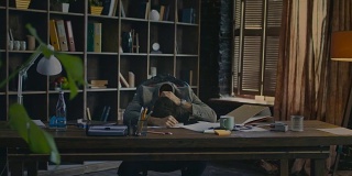 疲惫的商人躺在办公室的桌子上。一个疲惫的男人在工作场所的办公桌上
