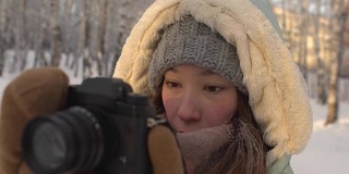 美丽的年轻女子在冬天的衣服，手套和羊毛帽子拍摄雪山森林针织相机