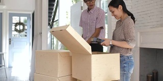 搬到新家后，一对亚洲夫妇正在搬箱子和拆包