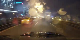 快速城市行驶夜间道路POV时间推移的挡风玻璃和车罩，雨夜，雨滴在玻璃上