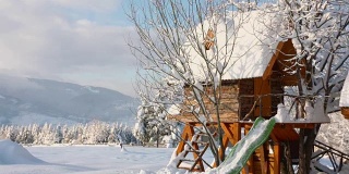 在阳光明媚的日子里，孩子们在白雪覆盖的山上玩耍的小房子