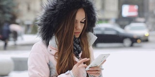一名年轻女子在冬日下雪天使用智能手机
