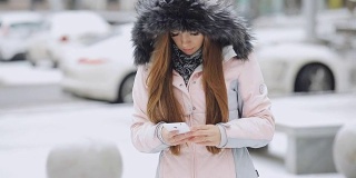 一名女子在冬日下雪天使用智能手机应用程序