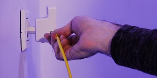 人将以太网线插入在墙上的电源插座中的WiFi扩展器设备中