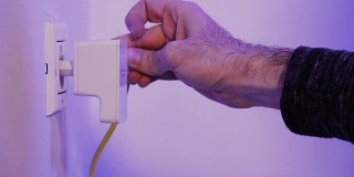 人将以太网线插入在墙上的电源插座中的WiFi扩展器设备中