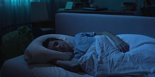 疲惫的年轻人在辛苦工作一天后，穿着白色t恤睡在他的床上