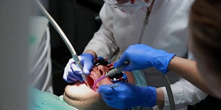 牙医和护士正在给一个病人补牙。用bormashenko钻牙，清除蛀牙和密封