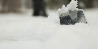 手机丢在雪地里。在后台的人离开它