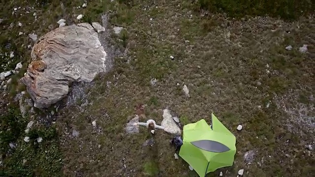 无人机飞过徒步者双臂张开，周围是风景优美的山湖景观