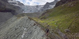 一名年轻男子在瑞士山脊上伸开双臂站立的无人机照片