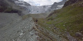 一名年轻男子在瑞士山脊上伸开双臂站立的无人机照片