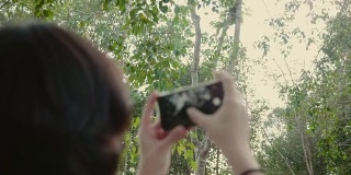 年轻女子在森林里拍照。