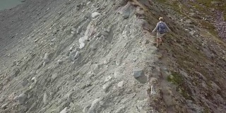 一名年轻女子在瑞士的山脊上徒步旅行的无人机镜头