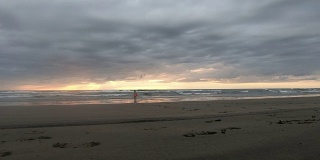 小男孩超级英雄在新西兰穆拉瓦伊海滩玩日落