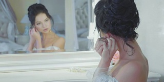 在豪华室内，一个女孩在镜子前戴着耳环