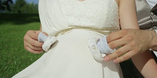 慢镜头:一对认不出来的新婚夫妇用手指玩婴儿鞋。