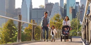 年轻的家庭在曼哈顿人行桥上推着婴儿车散步