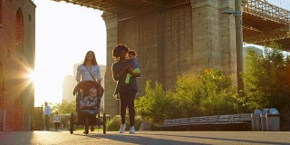 两位母亲带着蹒跚学步的孩子在曼哈顿的桥下行走