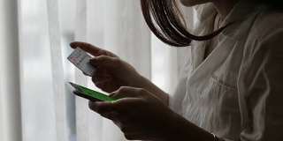 年轻女子使用智能手机和信用卡进行网上银行